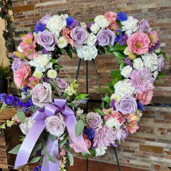 Heart-shaped floral wreath with lavender roses and pink blooms on an easel