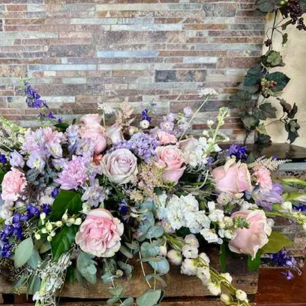 Large pastel floral arrangement with pink and white roses and purple flowers