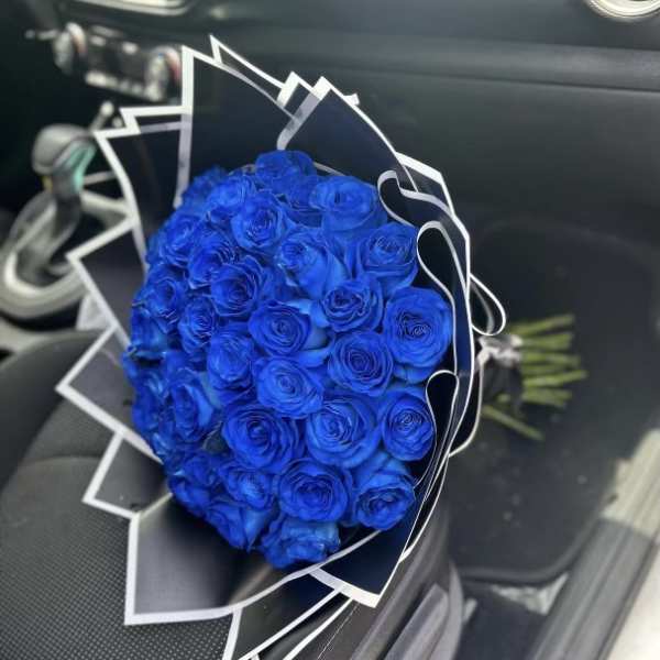 Bouquet of vivid blue roses wrapped in black and white paper