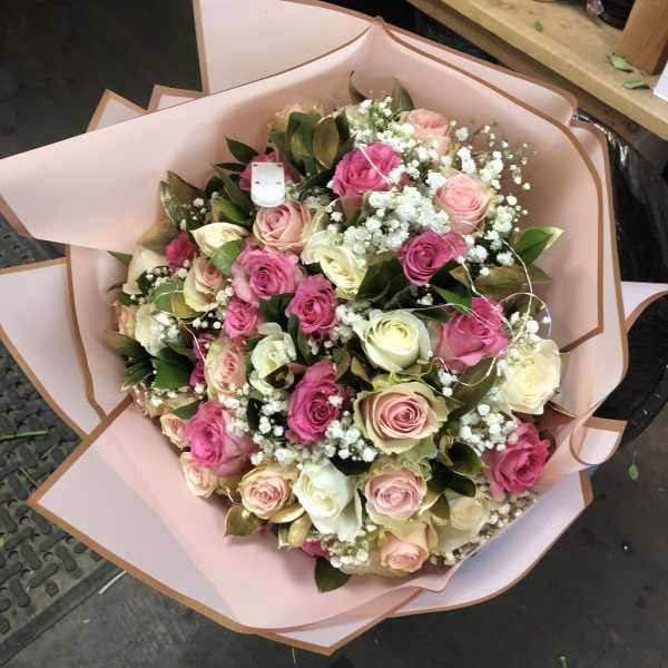 Bouquet of pink, cream, and white roses wrapped in blush paper