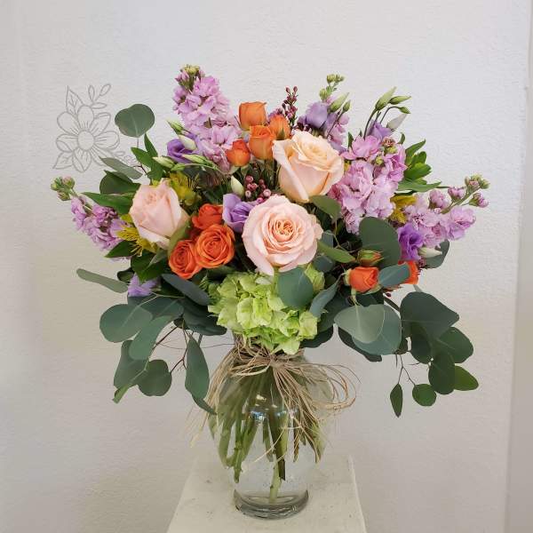 Mixed bouquet of roses and purple flowers in a glass vase