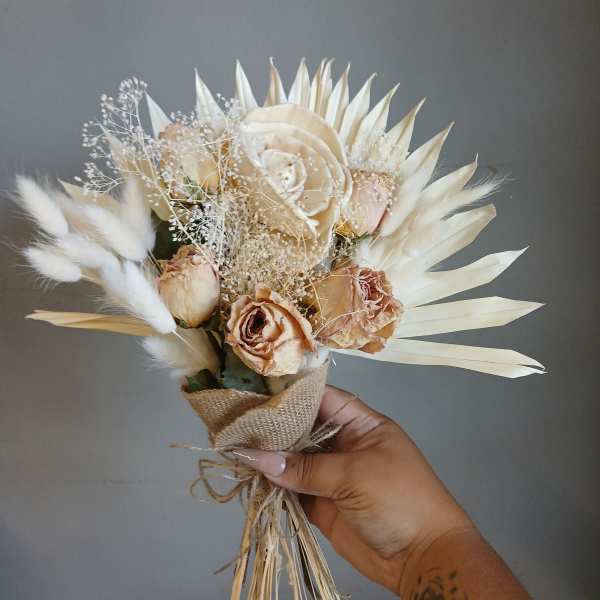 Small bouquet of cream roses and dried white accents wrapped in burlap