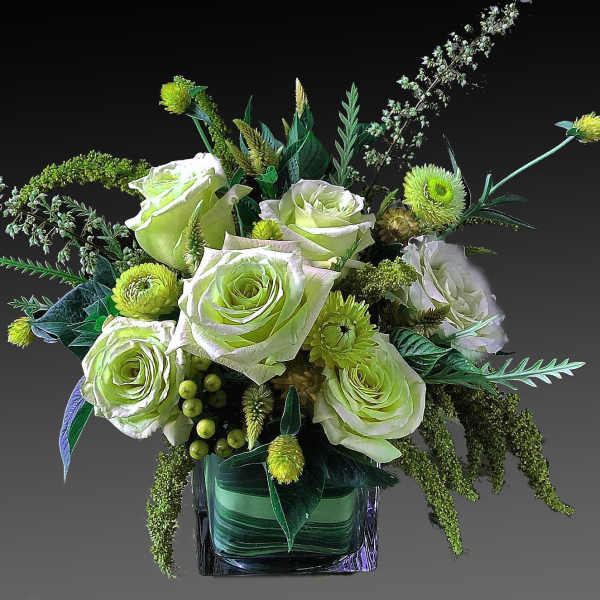 Green and white rose arrangement in a square glass vase