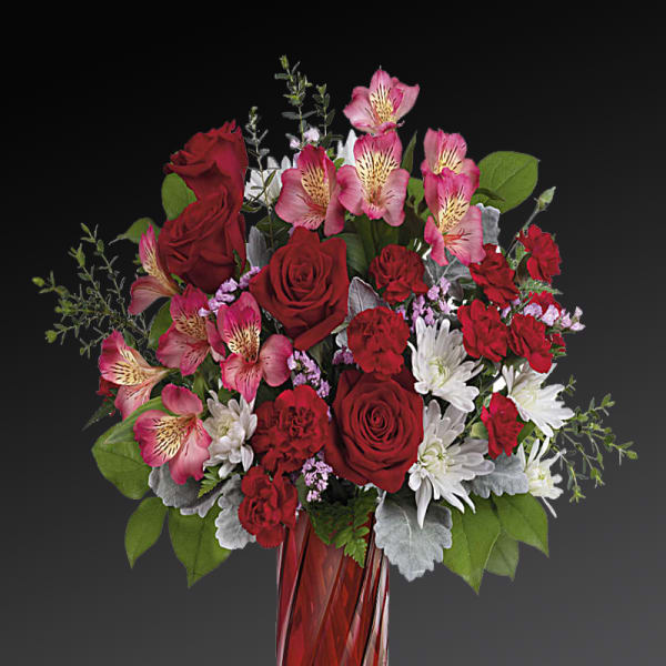 Red roses and pink alstroemeria in a red glass vase
