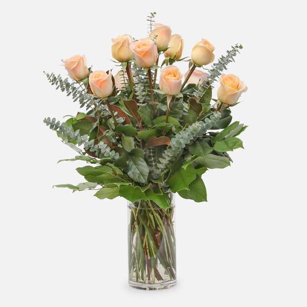 Peach roses in a clear glass vase with eucalyptus