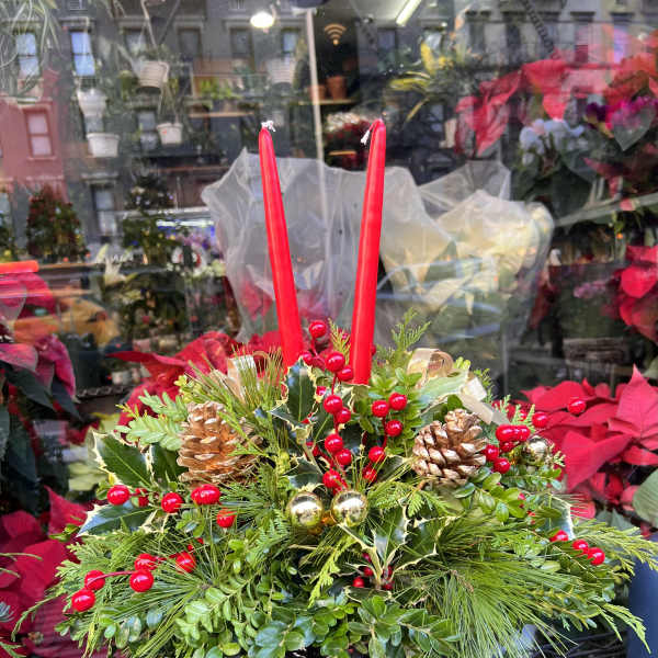 Holiday centerpiece with red candles, pinecones, and berries