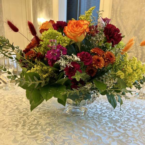 Mixed bouquet in a clear glass vase with orange and burgundy flowers