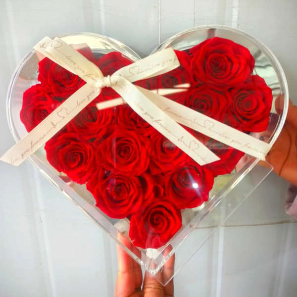 Heart-shaped box filled with red roses and tied with a white ribbon