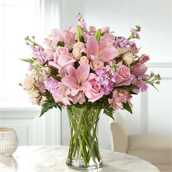 Pink bouquet of lilies and roses in a clear glass vase