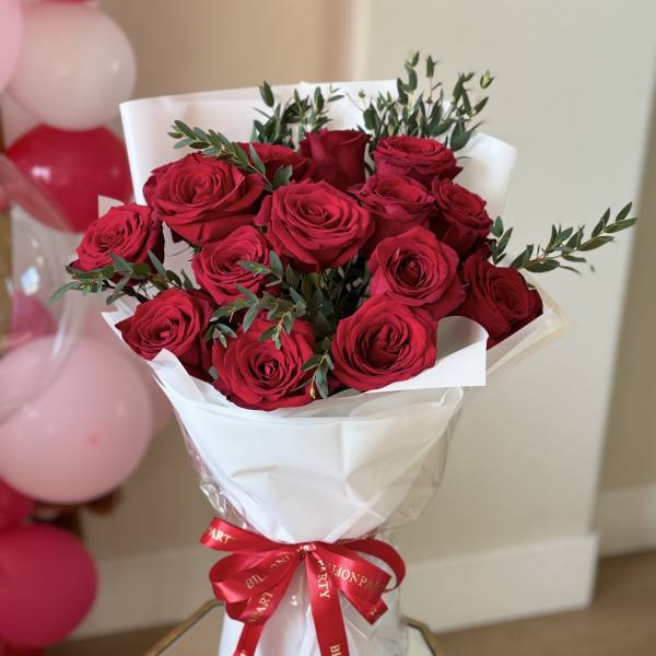 Bouquet of red roses wrapped in white paper with a red ribbon