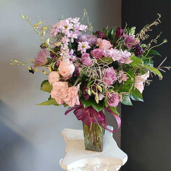 Pink and lavender mixed bouquet in a clear glass vase with a ribbon
