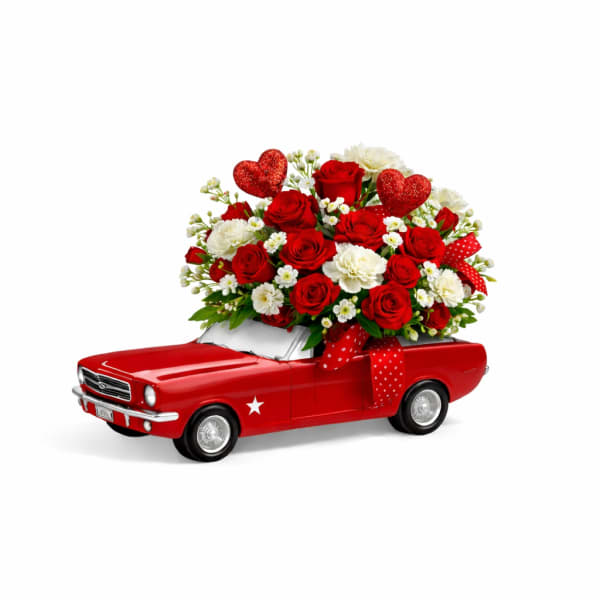 Red rose bouquet in a red toy car with heart decorations
