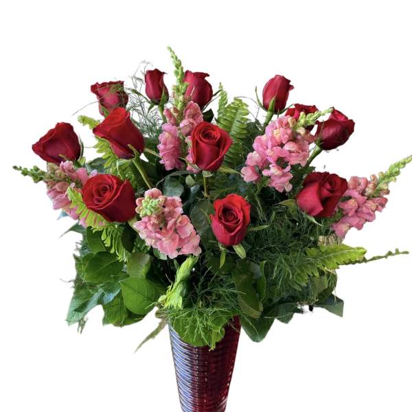 Red roses and pink snapdragons in a tall vase arrangement