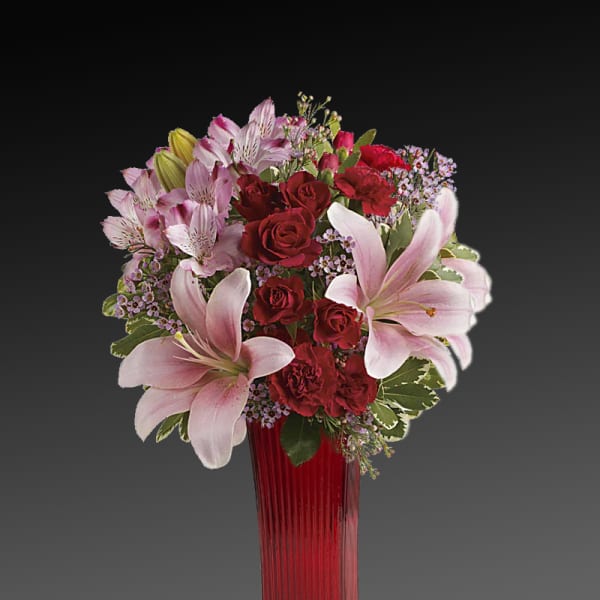 Bouquet of red roses and pink lilies in a tall red vase