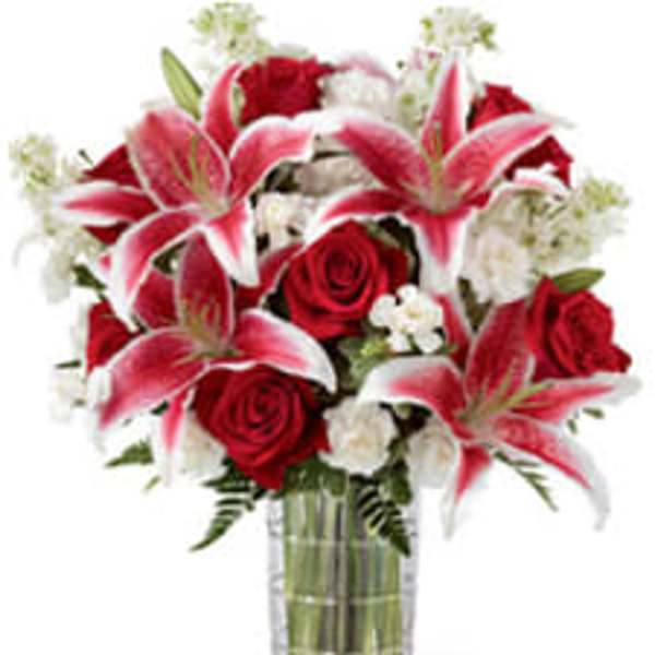 Bouquet of red roses and pink lilies in a clear glass vase