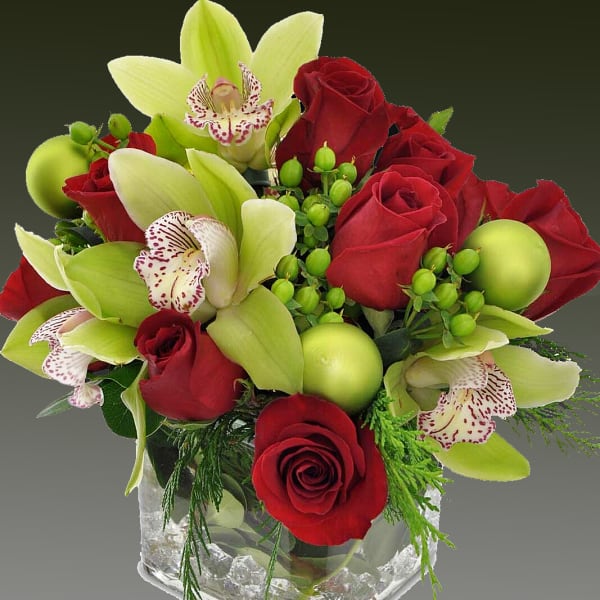 Red roses and green orchids in a clear square vase