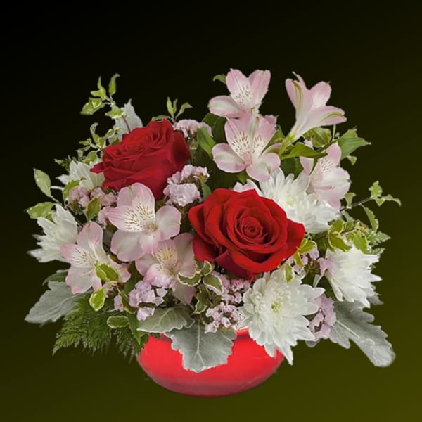 Red roses and pink lilies in a red vase with white blooms