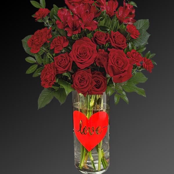 Red roses and carnations in a glass vase with a heart "love" decoration