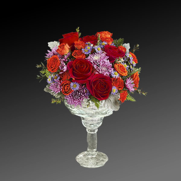 Mixed bouquet of red and orange roses in a clear glass pedestal vase