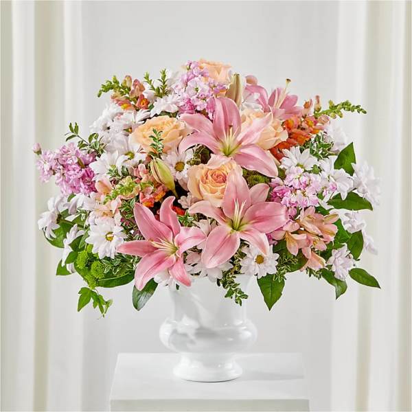 Pink lilies and peach roses in a white pedestal vase