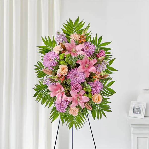 Standing floral spray with pink lilies, roses, and purple mums on an easel
