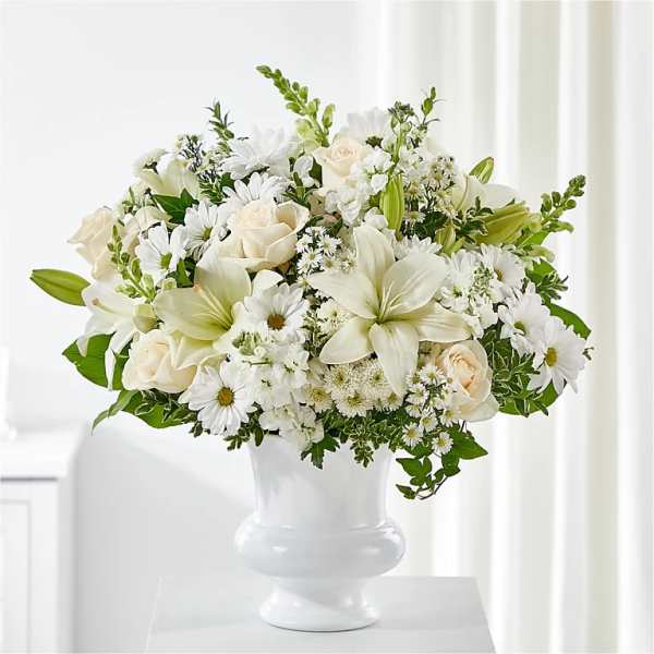 White floral arrangement in a white vase with roses and lilies