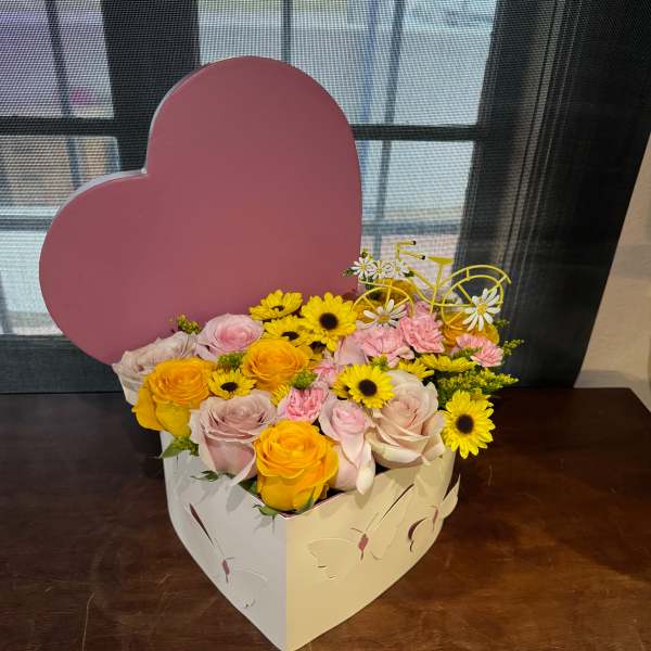 Heart-shaped box of pink and yellow flowers