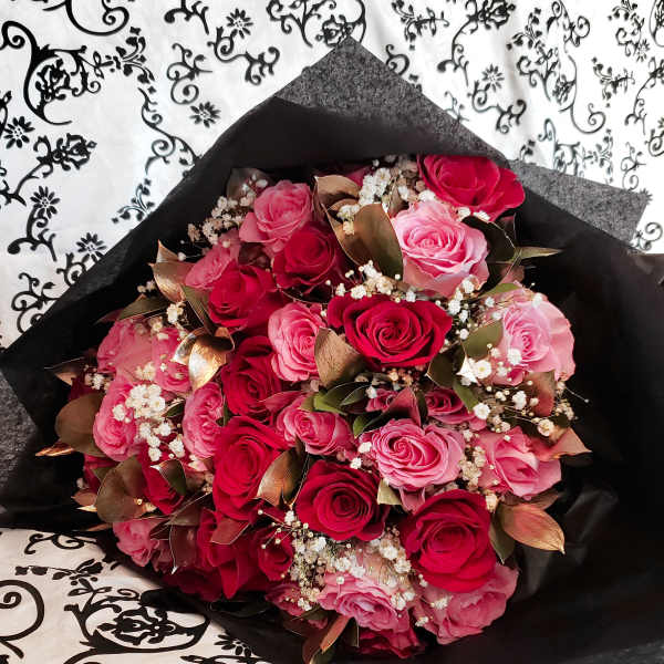 Bouquet of pink and red roses wrapped in black paper