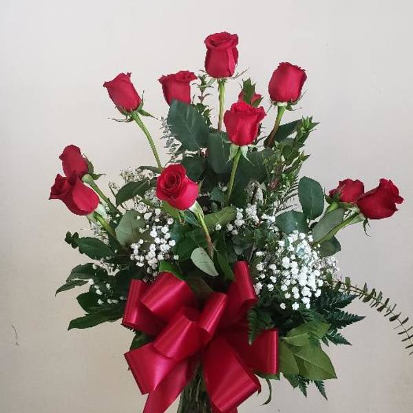 Red roses in a glass vase with a large red ribbon