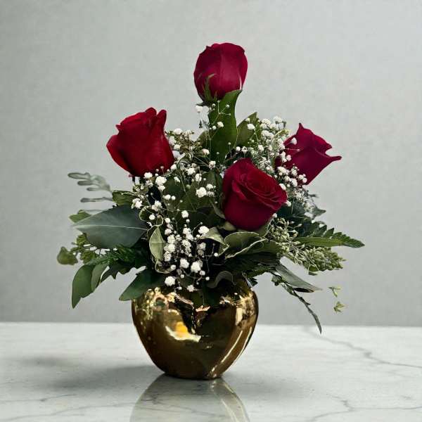 Red roses in a gold vase with white baby's breath