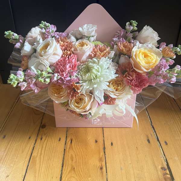 Pastel bouquet of roses, chrysanthemums, and carnations in a pink box