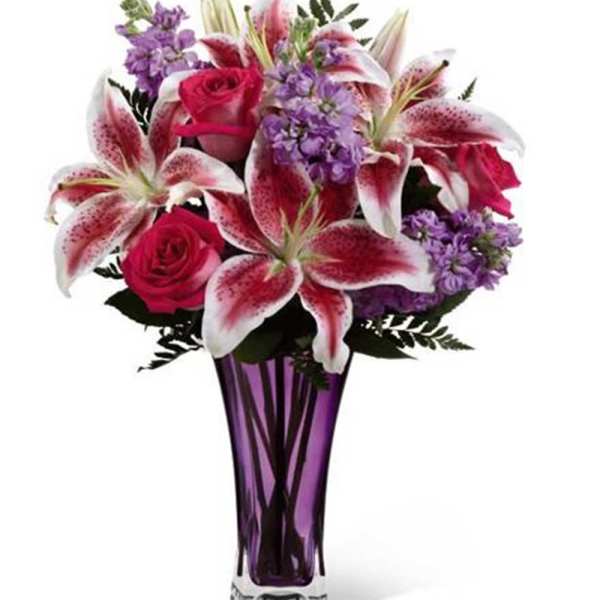 Bouquet of pink roses and lilies in a purple glass vase