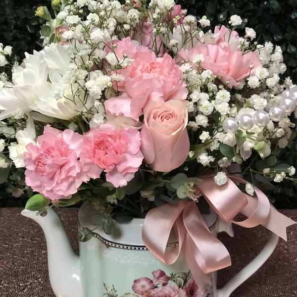 Pink and white flowers arranged in a decorative watering can