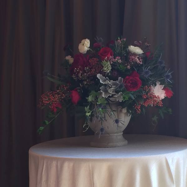 Large floral arrangement in a stone urn on a draped table