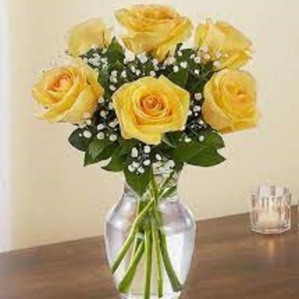 Yellow roses arranged in a clear glass vase with baby's breath