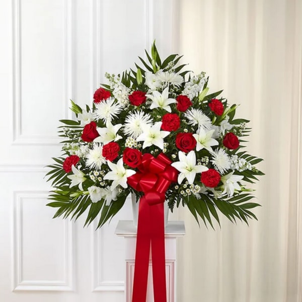 Large red and white floral spray with a red ribbon on a pedestal