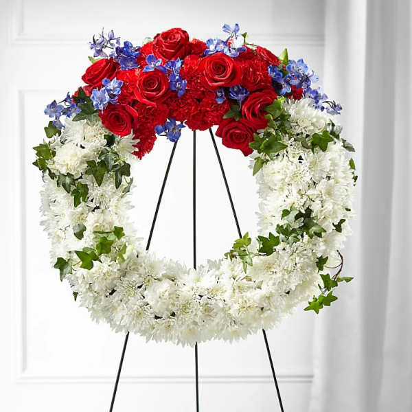 Circular funeral wreath with red roses, white chrysanthemums, and blue flowers