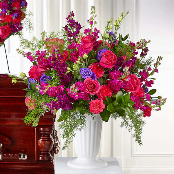 Large bouquet of pink and purple flowers in a white pedestal vase