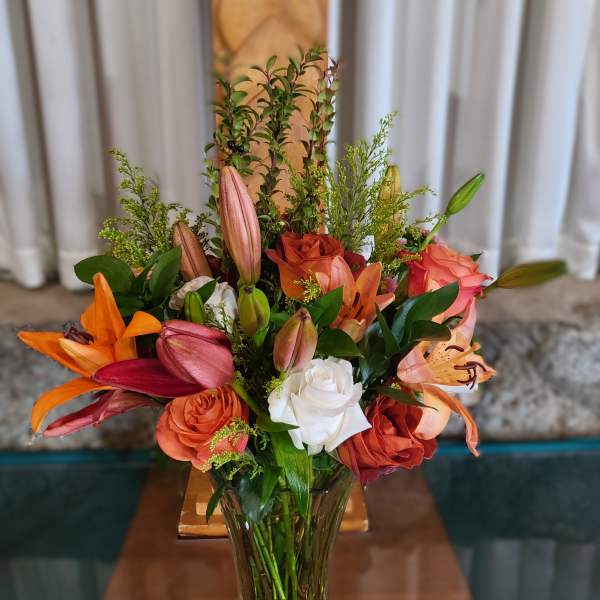 Mixed bouquet of lilies and roses in a clear glass vase