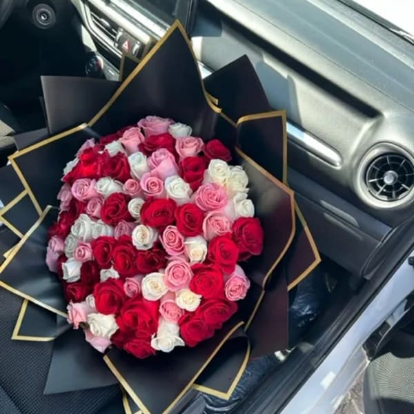 Large bouquet of red, pink, and white roses wrapped in black paper with gold trim
