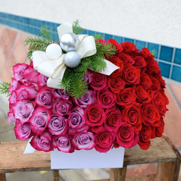 Heart-shaped bouquet of red and pink roses with a white ribbon bow