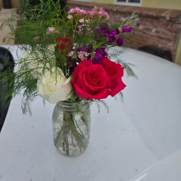 Bouquet of red and white roses in a clear glass jar vase