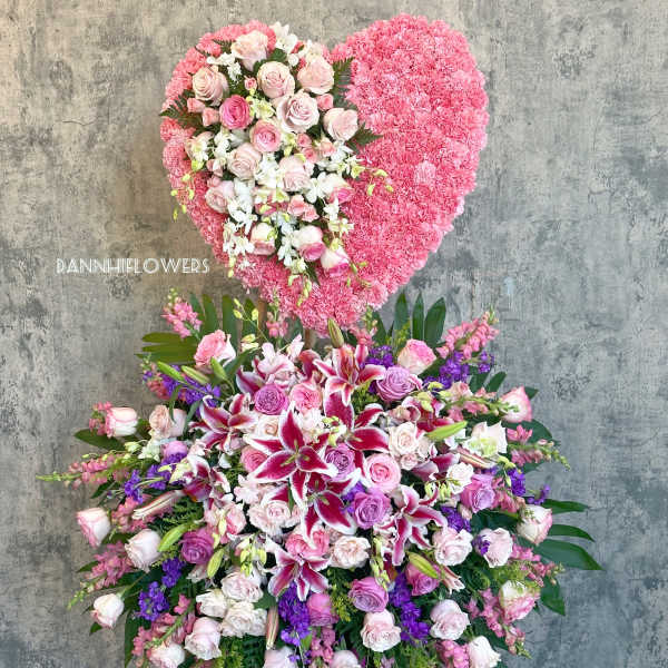 Large heart-shaped floral tribute with pink and white flowers on an easel