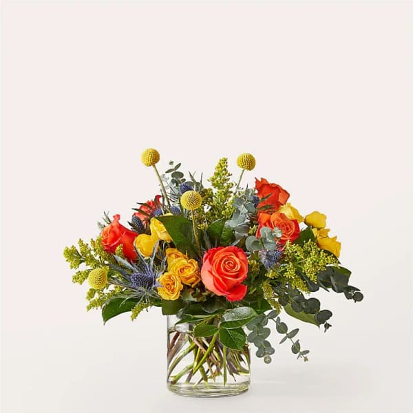 Mixed bouquet of orange and yellow roses in a clear glass vase