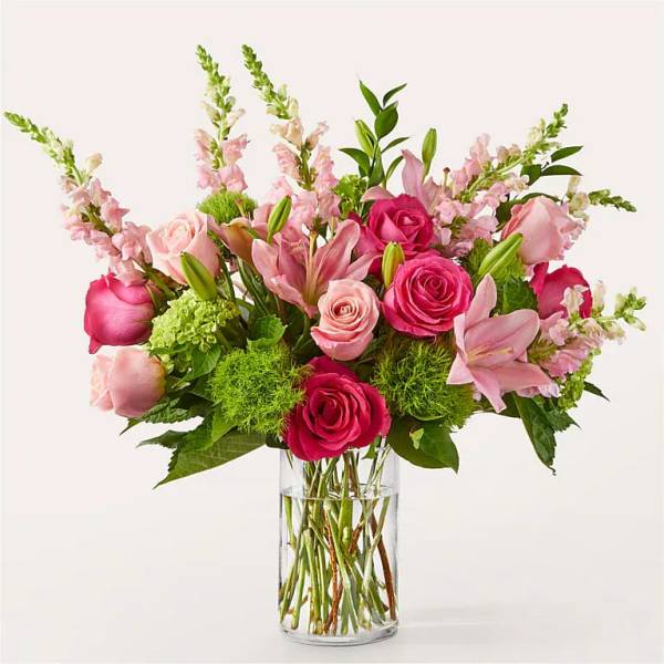 Pink roses and lilies arranged in a clear glass vase