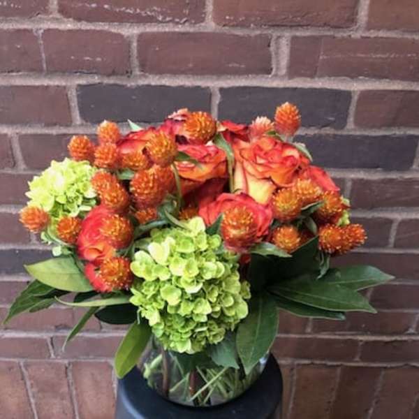 Bouquet of orange roses and green hydrangeas in a glass vase
