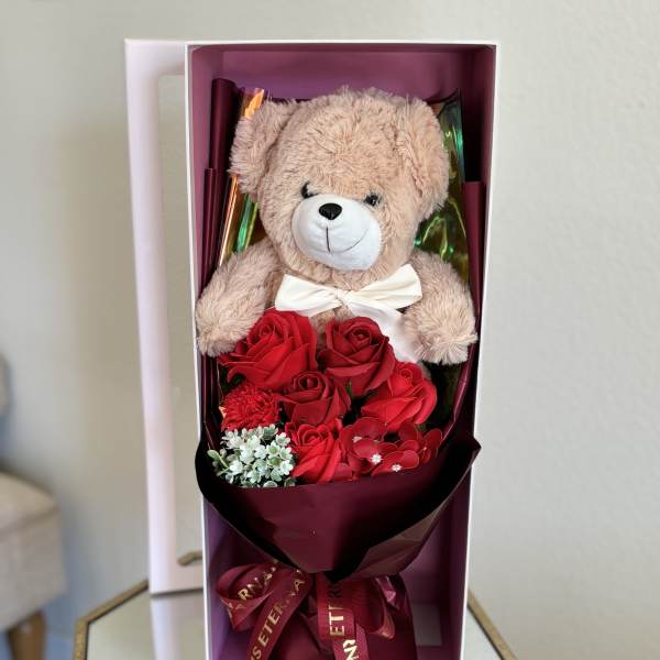 Teddy bear with red roses in a gift box