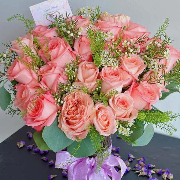 Pink rose bouquet in a glass vase with a lavender ribbon