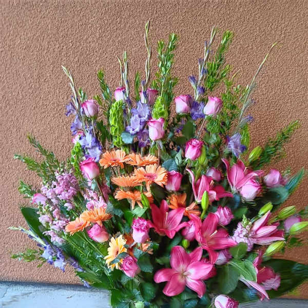 Large mixed bouquet of pink, purple, and orange flowers in a green vase