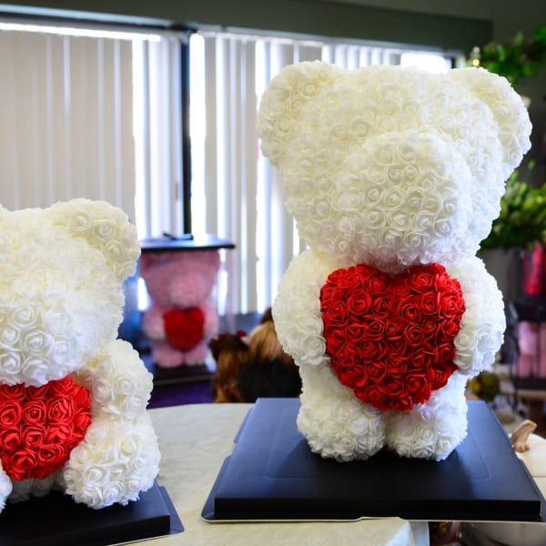 Two teddy bears made of white and red roses on black bases